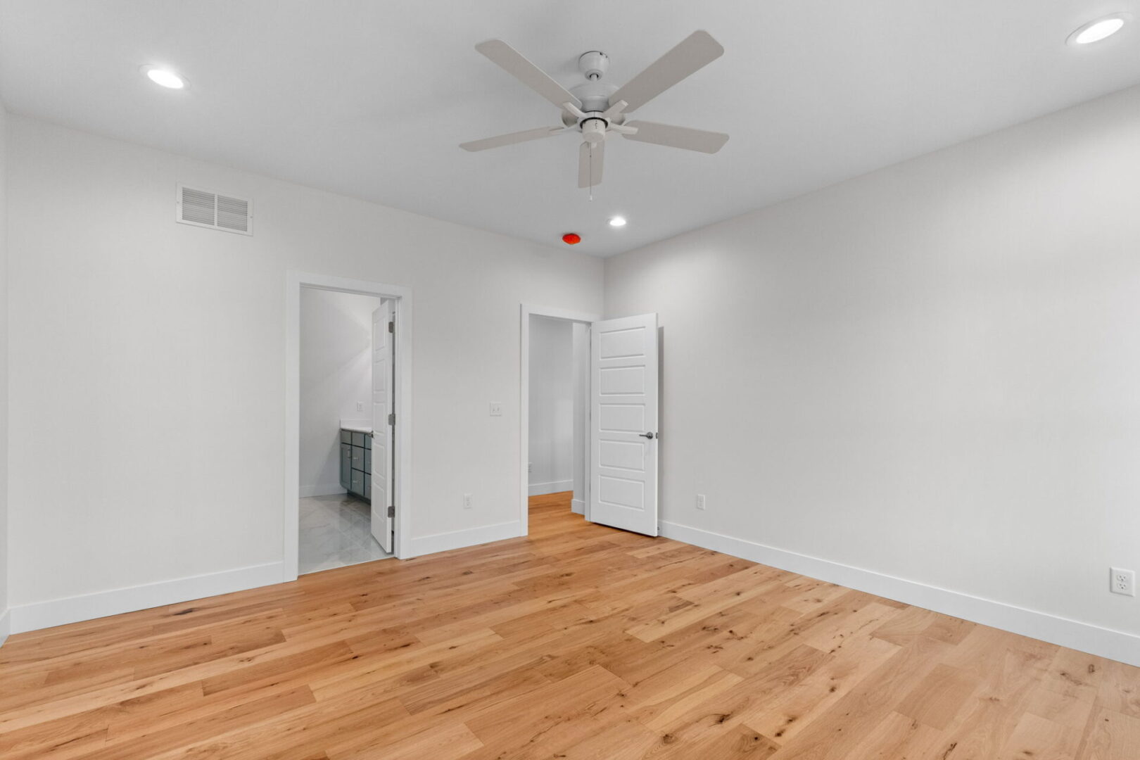 An empty room with a fan and two doors