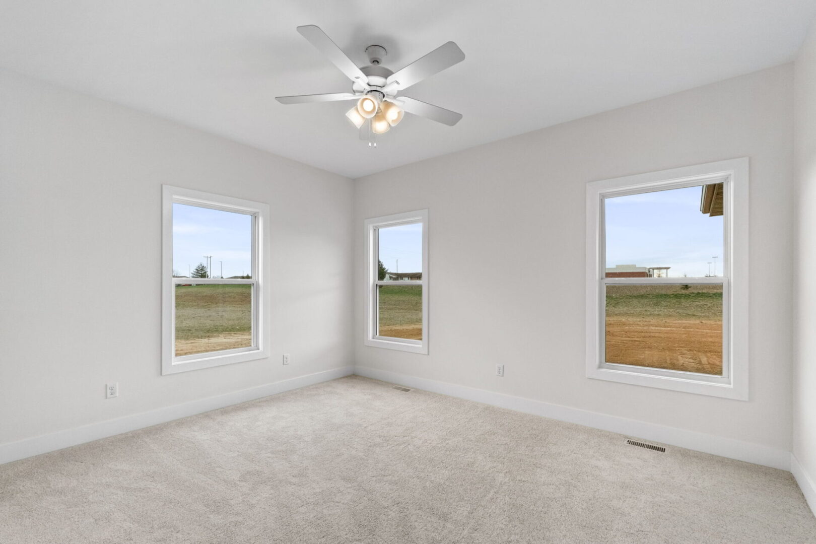 An empty room with a light fan and three windows
