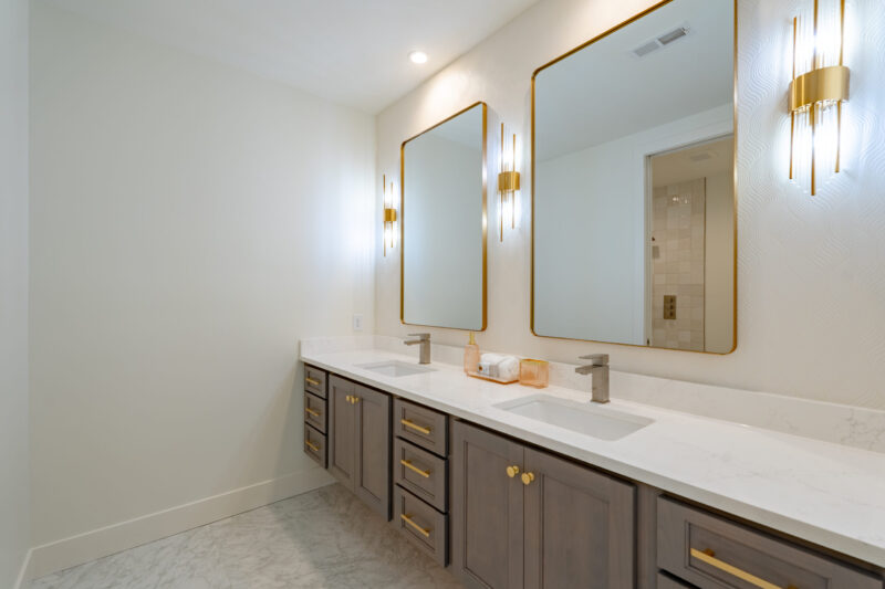 Bathroom has a floating vanity with double bowl sinks and stained cabinets.