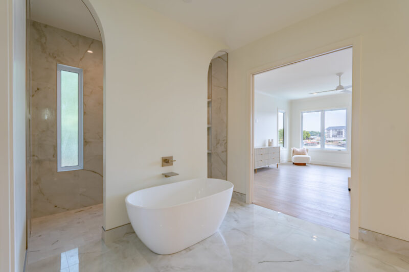 Primary suite bathroom with freestanding tub and arched entry to the large double head custom shower.