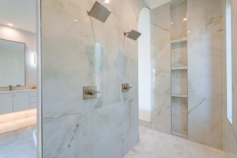 A Custom Luxury Primary Shower featuring double shower heads and custom-built niches.