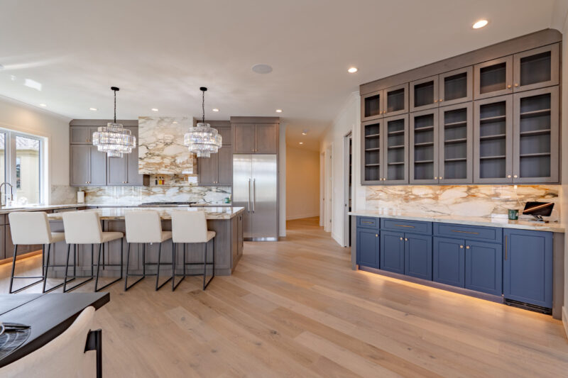 Luxurious large kitchen with custom stained cabinets and elegant countertops, with a two-toned bar.