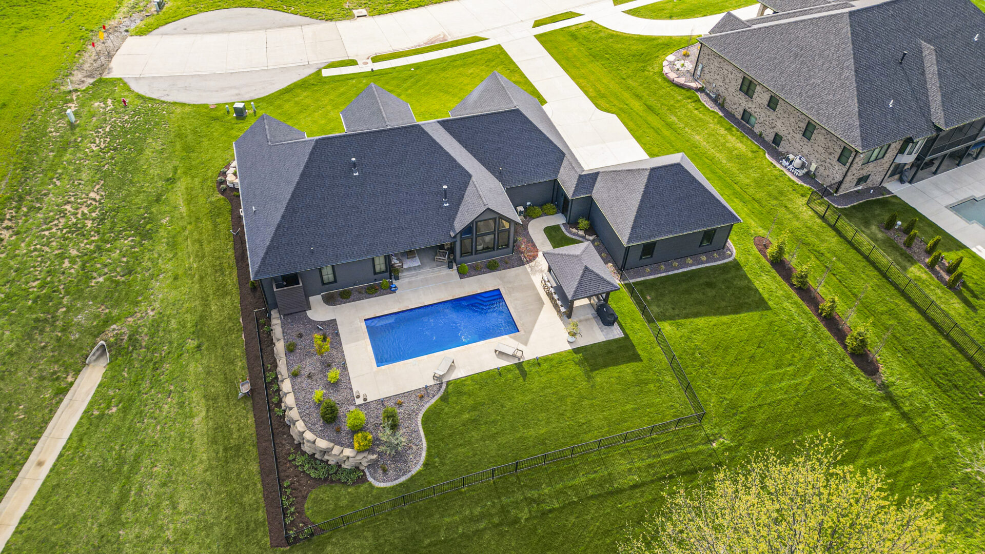 Pool Drone A contemporary mountain-style home features a stone and brick exterior. Over the front entrance, dark wooden beams stretch out, adding a touch of grandeur.