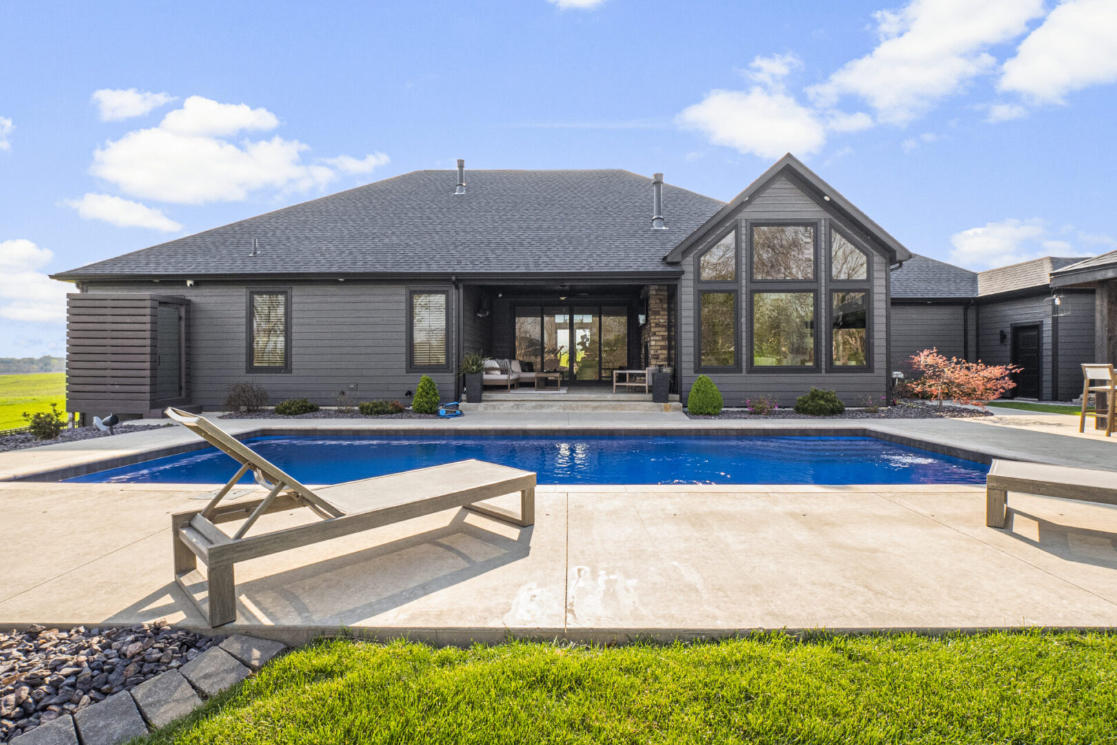 drone pool A contemporary mountain-style home features a stone and brick exterior. Over the front entrance, dark wooden beams stretch out, adding a touch of grandeur.